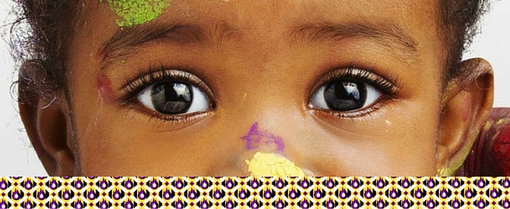 child with open eyes and colorful paint on the tip of their nose
